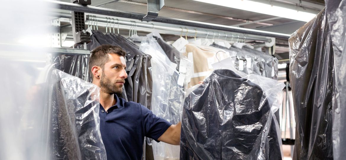 Male warehouse worker doing garment stock take in distribution warehouse