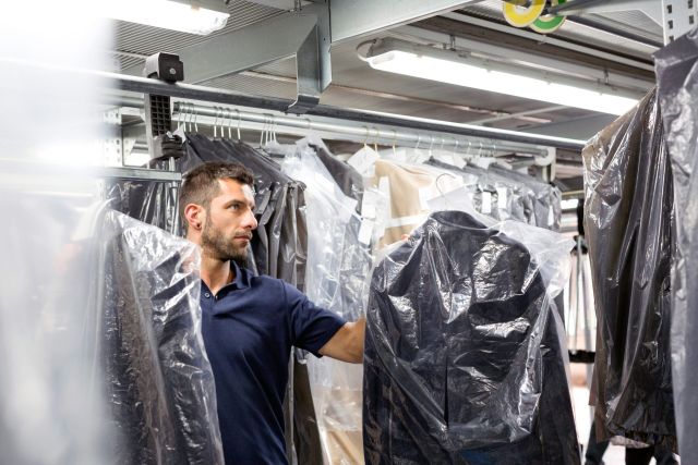 Male warehouse worker doing garment stock take in distribution warehouse